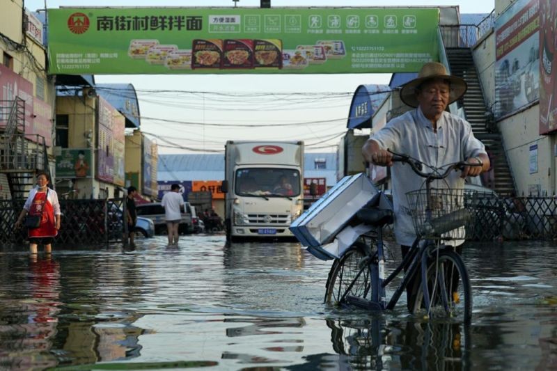In this Monday, July 26, 2021 file photo, a man carries goods on his bicycle as he walks out of the the Yubei Agricultural and Aquatic Products World in Xinxiang in central China's Henan Province. The Intergovernmental Panel on Climate Change report released on August 9, 2021, says warming already is smacking Earth hard and quickly with accelerating sea level rise, shrinking ice and worsening extremes such as heat waves, droughts, floods and storms. (AP  File Photo)