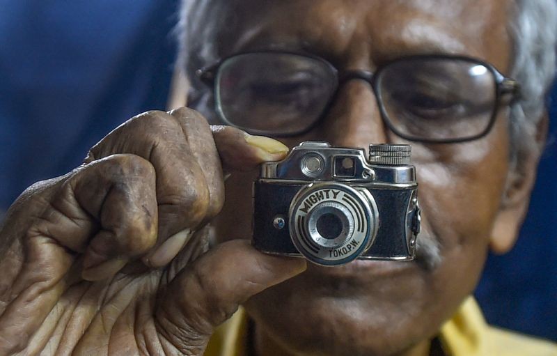 Veteran photographer Tapas Kumar Basu holds his old miniature 8mm Mionty film camera of 1930's, on the eve of World Photography Day, at his residence in Kolkata on August 18, 2021. (PTI Photo)