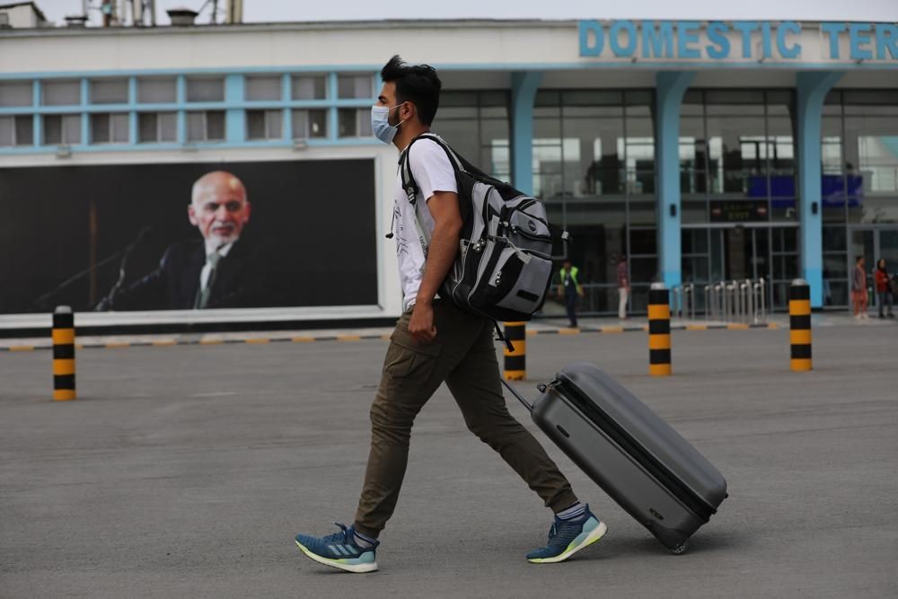 A passenger walks to the departures terminal of Hamid Karzai International Airport, in Kabul, Afghanistan, Saturday, Aug. 14, 2021. As a Taliban offensive encircles the Afghan capital, there's increasingly only one way out for those fleeing the war, and only one way in for U.S. troops sent to protect American diplomats still on the ground: the airport. (AP Photo/Rahmat Gul)