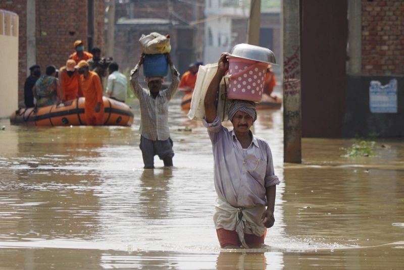 Varanasi: People carry their essential commodities as NDRF team evacuates people during a rescue operation at flooded Maruthi Nagar colony in Varanasi, Sunday, Aug 8, 2021. (PTI Photo)(