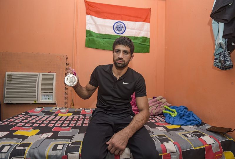 New Delhi: Tokyo Olympics Silver-medalist Wrestler Ravi Dahiya shows his medal in his room at Chhatrasal Stadium in New Delhi, Tuesday, Aug 10, 2021. The room where Dahiya has been staying for the last 11 years in Chhatrasal Stadium. Four wrestlers live together in this small room. Ravi Dahiya trains at  Stadium.  (PTI Photo/ Manvender Vashist)