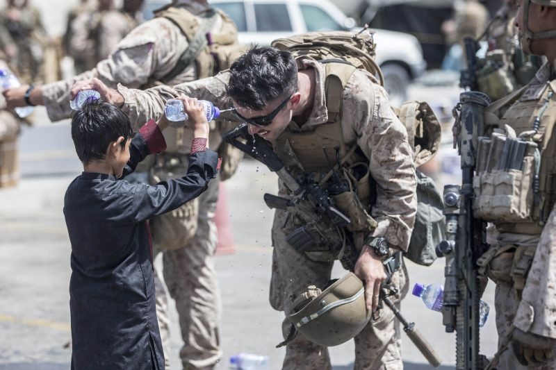 In this Aug. 21, 2021, photo provided by the U.S. Marine Corps, a Marine with Special Purpose Marine Air-Ground Task Force-Crisis Response-Central Command (SPMAGTF-CR-CC) and a child spray water at each other during an evacuation at Hamid Karzai International Airport in Kabul, Afghanistan. (AP/PTI Photo)
