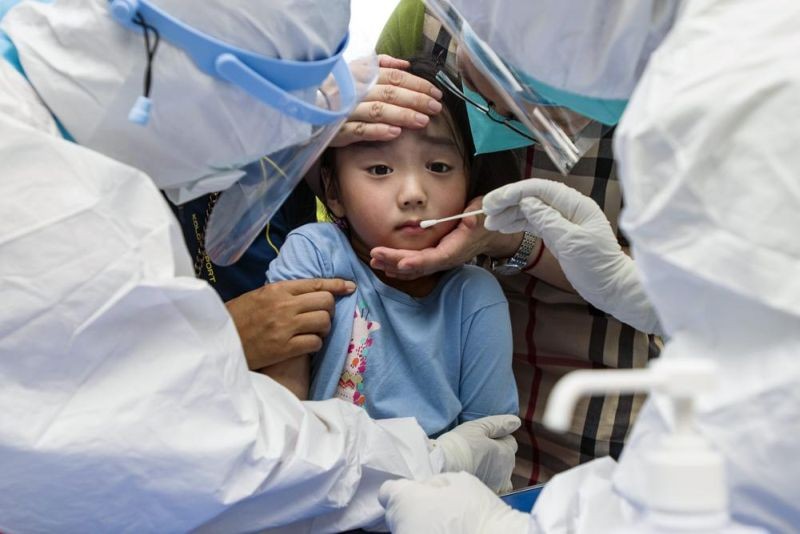 A child reacts to a throat swab during mass testing for COVID-19 in Wuhan in central China's Hubei province on August 3, 2021. The coronavirus’s delta variant is challenging China’s costly strategy of isolating cities, prompting warnings that Chinese leaders who were confident they could keep the virus out of the country need a less disruptive approach. (AP Photo)