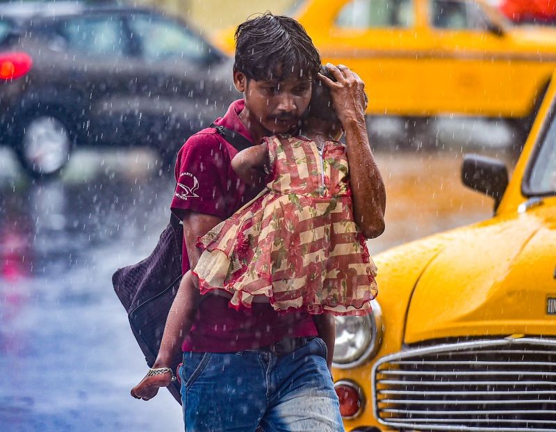 Kolkata: A man carrying her daughter rushes for a shelter during rain in Kolkata, Tuesday, Sept 14, 2021. (PTI Photo/Swapan Mahapatra)