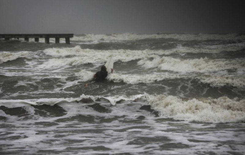 A surfer tries to paddle through the surf as wind and rain from Tropical Storm Nicholas batters the area on September 13, 2021, along the seawall in Galveston, Texas. (AP Photo)