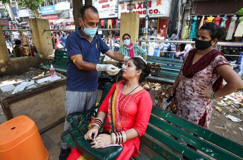 A health worker collects swab sample of a woman for COVID-19 test, at a market in Jammu on Sept. 29, 2021. (PTI Photo)