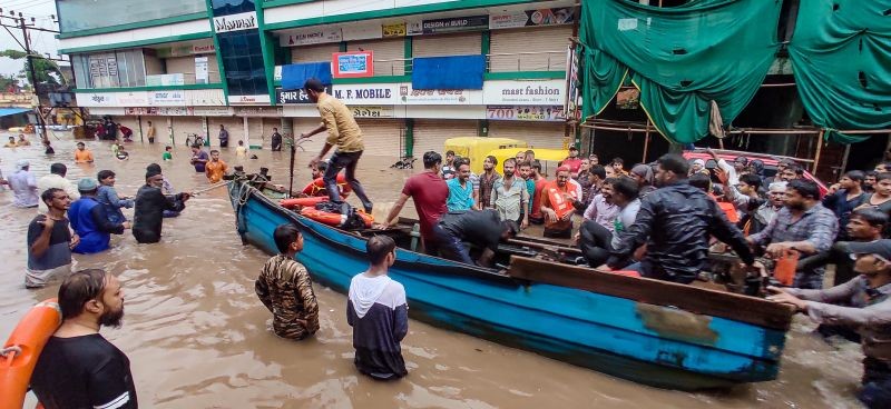 People use a boat to wade through a flooded street after heavy rain in Jamnagar on September 13. (PTI Photo)