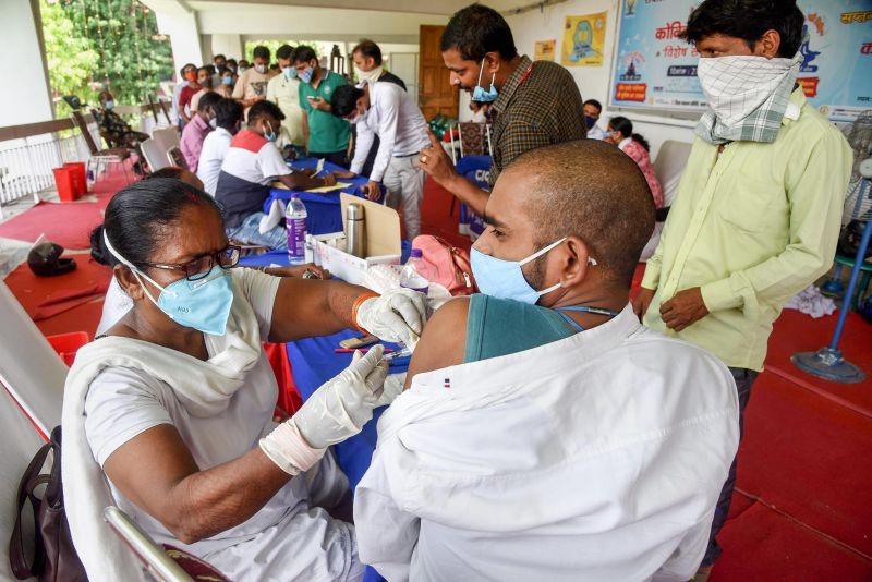 A health worker administers a dose of COVID-19 vaccine to beneficiaries as others wait for their turn, in Patna. (PTI File Photo)