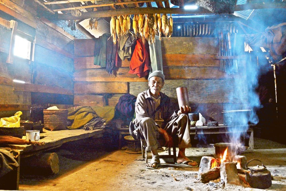 An elderly man holds a bamboo mug while seating by the fireplace in a kitchen somewhere in Nagaland. International Day of Older Persons is celebrated on October 1 every year. (Morung Photo)