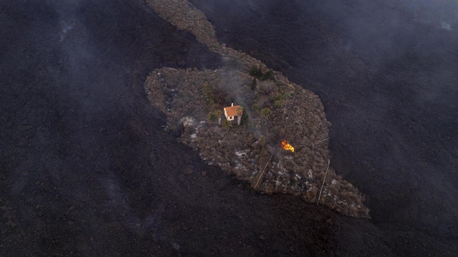 La Palma : In this photo provided by iLoveTheWorld, a house remains intact as lava flows after a volcano erupted near Las Manchas on the island of La Palma in the Canaries, Spain, Monday, Sept. 20, 2021. A dormant volcano on a small Spanish island in the Atlantic Ocean erupted on Sunday, forcing the evacuation of thousands of people. Huge plumes of black-and-white smoke shot out from a volcanic ridge where scientists had been monitoring the accumulation of molten lava below the surface. AP/PTI