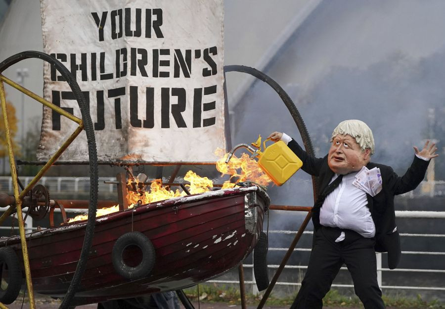 Glasgow: A performer from environmental campaign Ocean Rebellion dressed as Prime Minister Boris Johnson sets light to the sail of a small boat which reads "Your Children's Future" during a protest on the banks of the River Clyde, close to the site of the upcoming United Nations COP26 conference on climate, in Glasgow, Scotland, Wednesday Oct. 27, 2021.AP/PTI