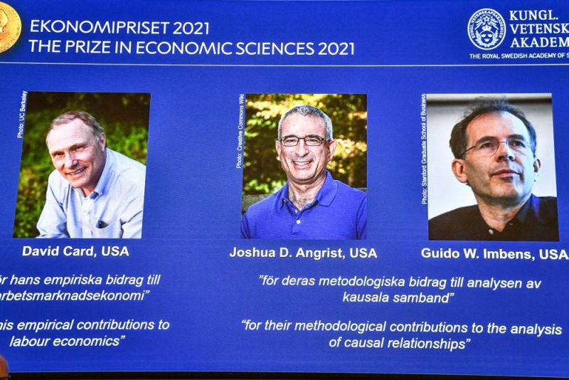 From left, on the screen are the winners of the 2021 Nobel prize for economics; David Card of the University of California at Berkeley; Joshua Angrist from the Massachusetts Institute of Technology; and Guido Imbens from Stanford University, announced during a press conference at the Royal Swedish Academy of Sciences, in Stockholm, Sweden on October 11, 2021. (AP Photo)