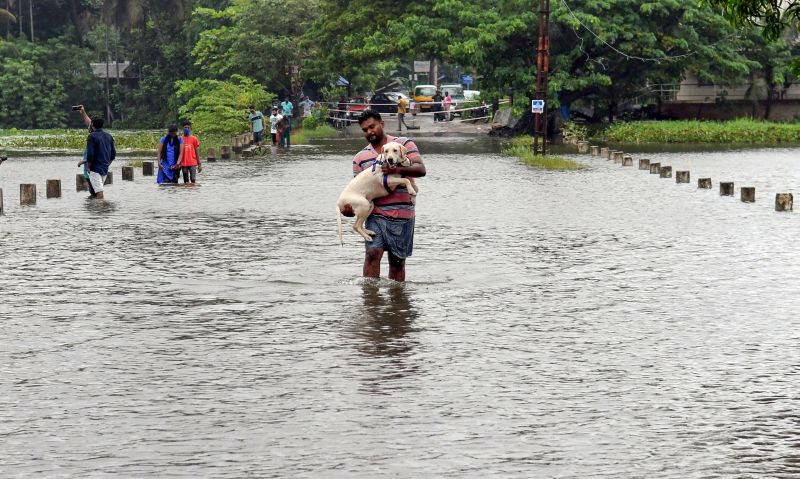 Thiruvananthapuram: A man carrying his pet dog wades through the flooded Vellayani Kakkamoola road during heavy rain in Thiruvananthapuram, Saturday, Oct, 16, 2021. (PTI Photo)
