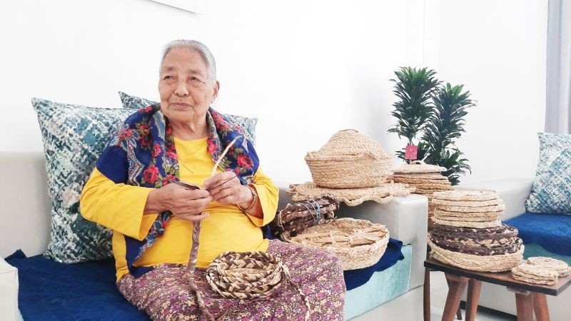 Otsü Pangerla sits in her living room as she weaves baskets out of corn husks. (Morung Photo)