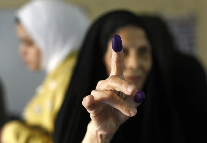 An Iraqi elderly woman shows her ink-stained finger after casting her vote inside a polling station in the country's parliamentary elections in Baghdad, Iraq on October 10, 2021. Iraq closed its airspace and land border crossings on Sunday as voters headed to the polls to elect a parliament that many hope will deliver much needed reforms after decades of conflict and mismanagement. (AP Photo)