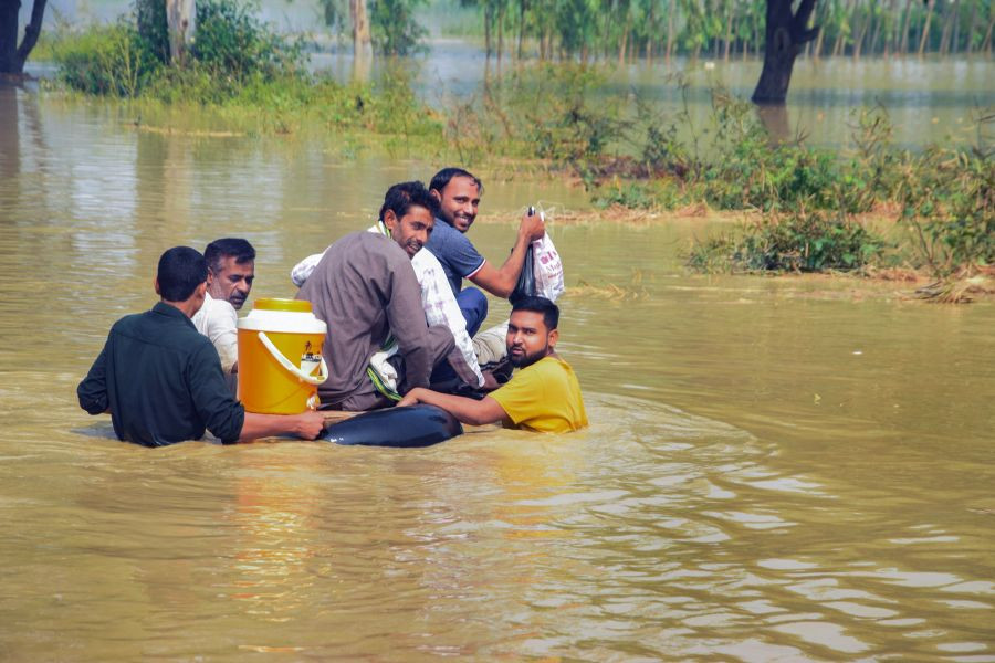 Moradabad: Commuters wade through a flooded road at Mundha Pandey area in Moradabad, Wednesday, Oct. 20, 2021. (PTI Photo)