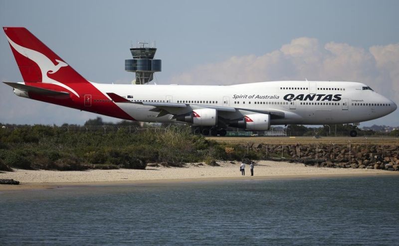 In the Aug. 20, 2015, file photo, two people watch from a beach as a Qantas plane taxies on the runway at Sydney Airport in Sydney, Australia. Australia has outlined plans to lift its pandemic ban on its vaccinated citizens traveling overseas from November but no date has yet been set for welcoming international tourists back. (AP File Photo)