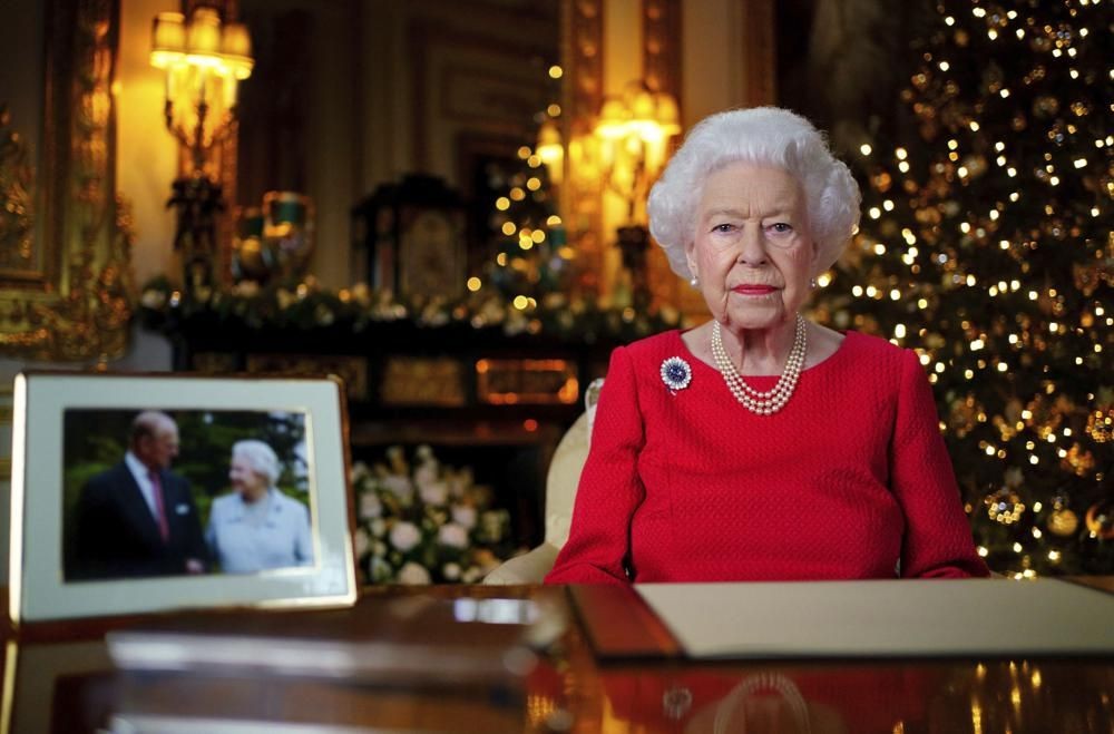 In this undated photo issued on Thursday Dec. 23, 2021, Britain's Queen Elizabeth II records her annual Christmas broadcast in Windsor Castle, Windsor, England. The photograph at left shows The Queen and Prince Philip taken in 2007 at Broadlands to mark their Diamond wedding anniversary. (Victoria Jones/Pool via AP)