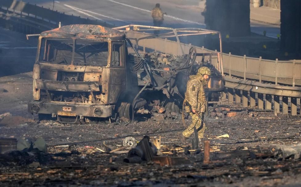 A Ukrainian soldier walks past debris of a burning military truck, on a street in Kyiv, Ukraine, Saturday, Feb. 26, 2022. Russian troops stormed toward Ukraine’s capital Saturday, and street fighting broke out as city officials urged residents to take shelter. (AP Photo/Efrem Lukatsky)