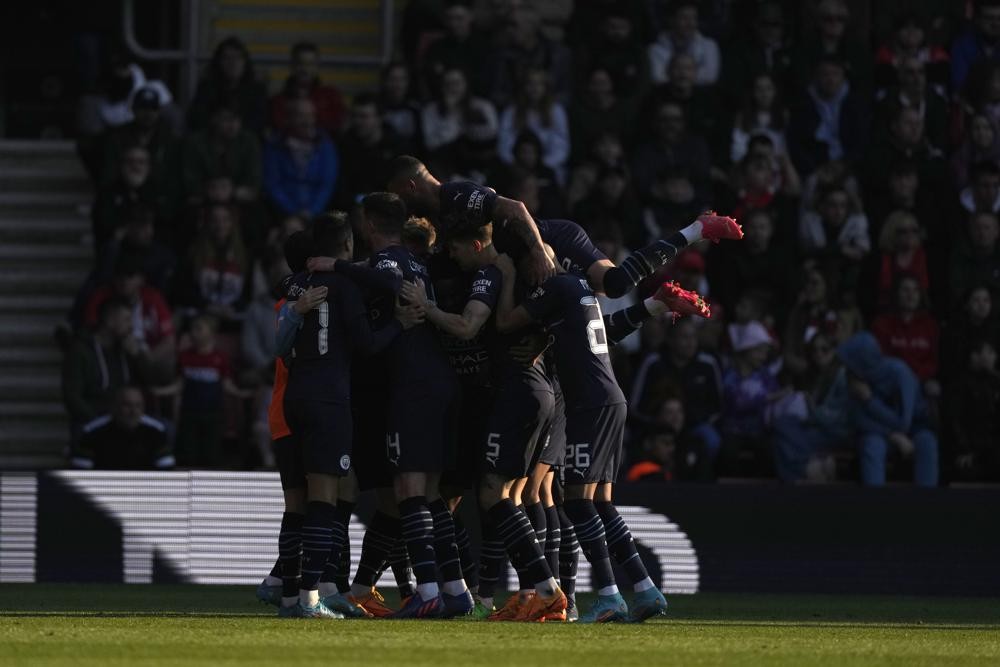 Manchester City players celebrate their side's third goal during the English FA Cup soccer match between Southampton and Manchester City at St Mary's stadium in Southampton, England, Sunday, March 20, 2022. (AP Photo/Alastair Grant)