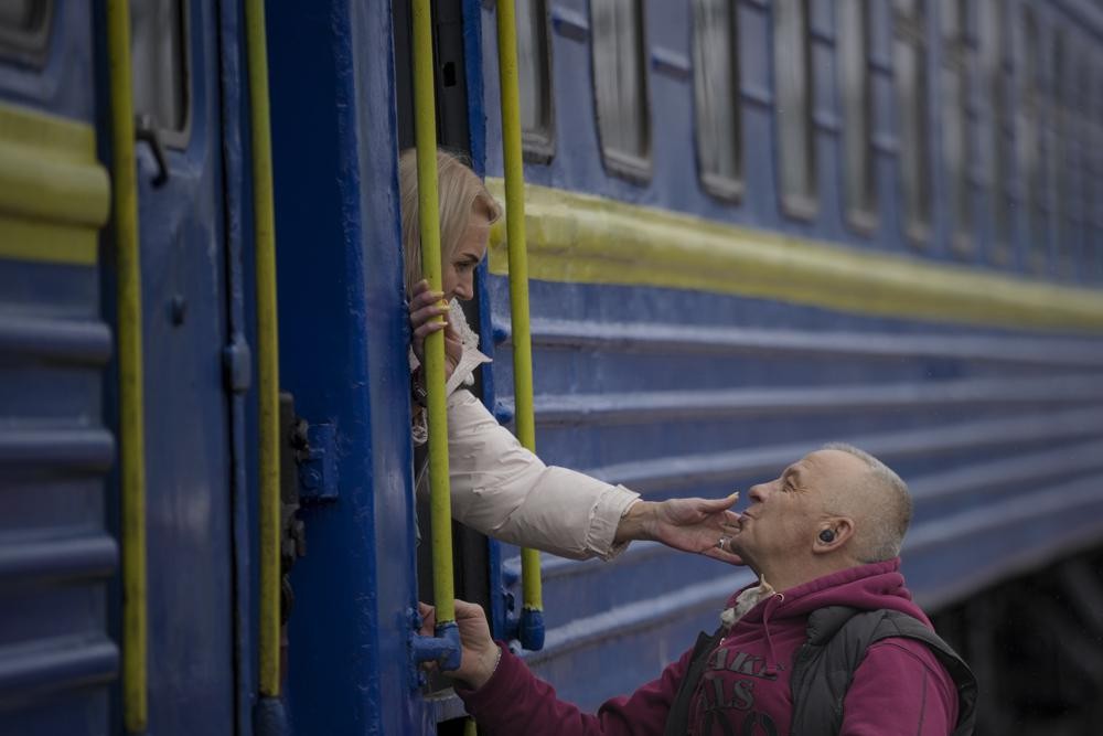 A woman bids a man goodbye after boarding a Lviv bound train, in Kyiv, Ukraine, Thursday, March 3, 2022. Ukrainian President Volodymyr Zelenskyy's office says a second round of talks with Russia aimed at stopping the fighting that has sent more than 1 million people fleeing over Ukraine's borders, has begun in neighboring Belarus, but the two sides appeared to have little common ground. (AP Photo/Vadim Ghirda)