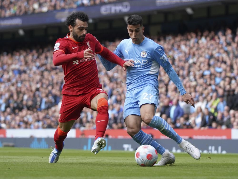 Liverpool's Mohamed Salah, left, duels for the ball with Manchester City's Joao Cancelo during the English Premier League soccer match between Manchester City and Liverpool, at the Etihad stadium in Manchester, England, Sunday, April 10, 2022. (AP Photo/Jon Super)