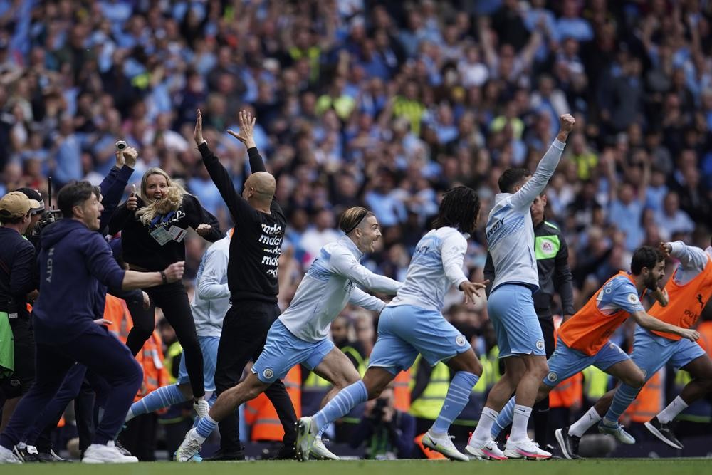 Manchester City's head coach Pep Guardiola and his teammates celebrate after winning the English Premier League soccer match between Manchester City and Aston Villa at the Etihad Stadium in Manchester, England, Sunday, May 22, 2022. Manchester City won the match against Aston Villa and secured the 2022 Premier League title. (AP Photo/Dave Thompson)