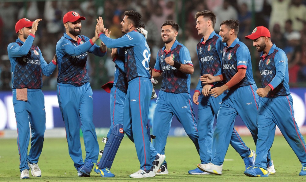 Afghanistan's Mujeeb ur Rahman celebrates the wicket of England's Chris Woakes with teammates during the ICC Men's Cricket World Cup match between Afghanistan and England at Arun Jaitley Stadium, in New Delhi, Sunday, October 15, 2023. (Photo: IANS/Raj Kumar)