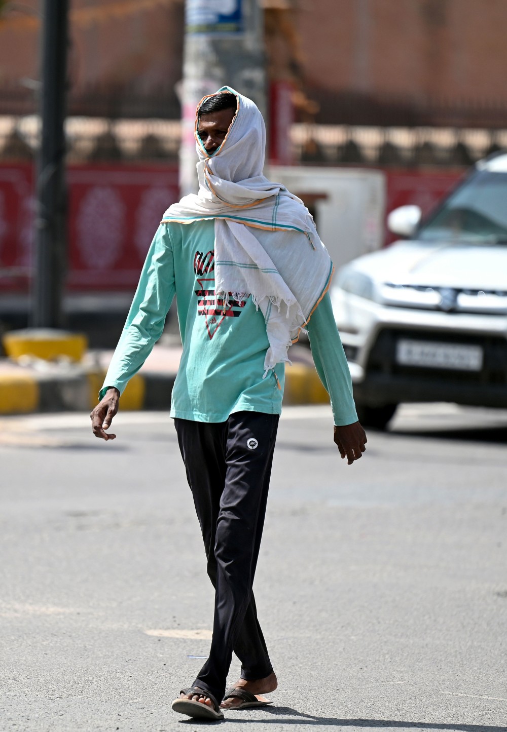 A man covers his head while walking on a road amid scorching heat in Bikaner on Sunday, June 08, 2025. (Photo: IANS)