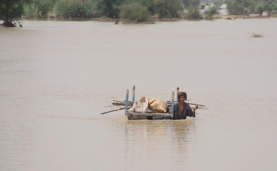 A woman with her belongings wades through flood water in Rajanpur district of Pakistan's Punjab province on Aug. 27, 2022. The death toll in separate accidents caused by heavy rains across Pakistan has surged to 1,000 since the start of monsoon season on June 14, the National Disaster Management Authority (NDMA) said on Saturday night. (Photo by Mansoor/Xinhua)