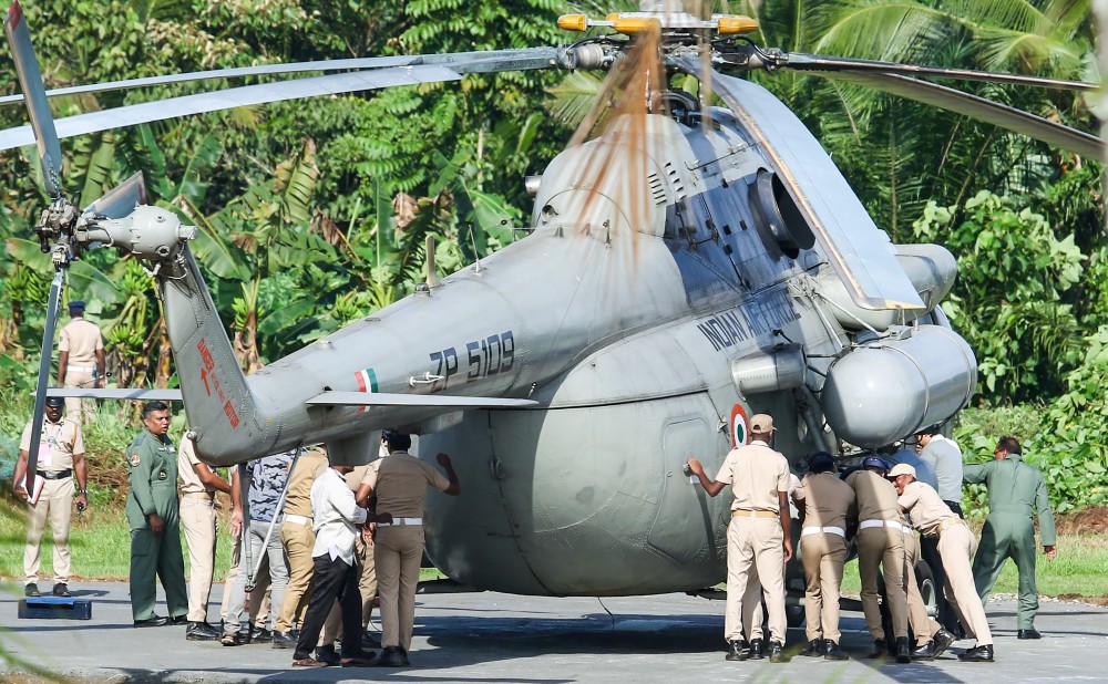 Police personnel push a helicopter that sank slightly into freshly laid concrete at Pramadam helipad after President Droupadi Murmu’s arrival from Thiruvananthapuram, in Sabarimala on Wednesday, October 22, 2025. (Photo: IANS)